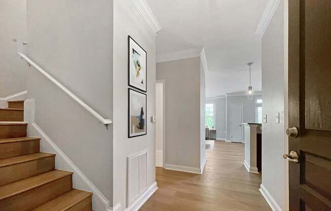 A hallway with a staircase and a doorway leading to another room.