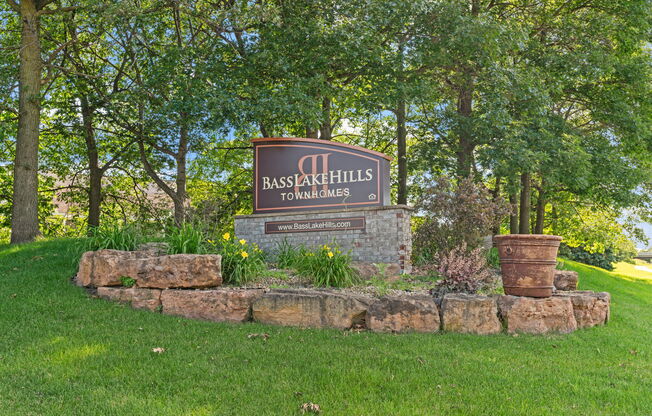 a stone retaining wall with a sign in front of trees