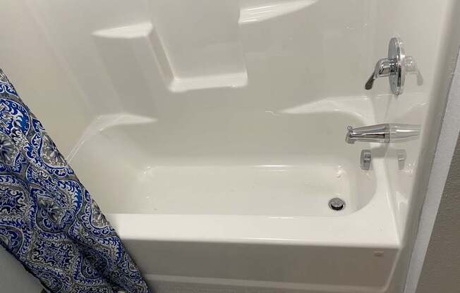 A white bathtub with a silver faucet and a blue and white towel hanging on the side.