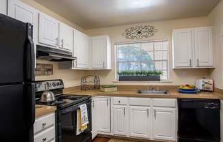 A kitchen with black appliances and white cabinets.