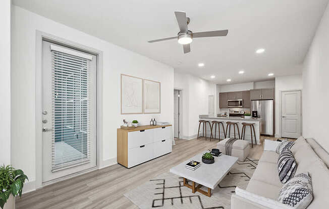 Model Living Room with Wood-Style Flooring and View of Kitchen at Alta 3Eighty Apartments located in Aubrey, TX.