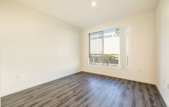 an empty living room with wood flooring and a window