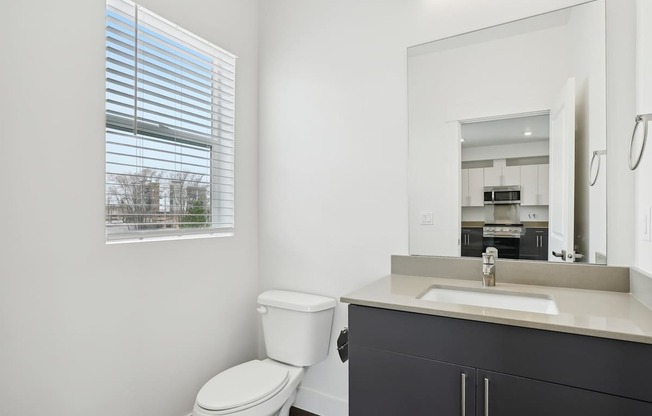 A bathroom with a toilet, sink, and mirror.