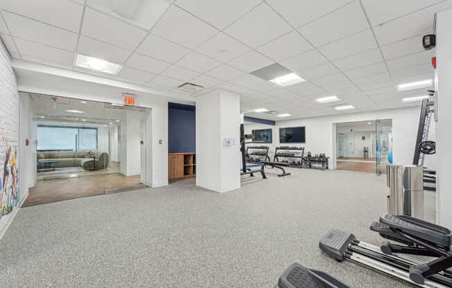 A gym with a variety of equipment including treadmills, weights and exercise machines.