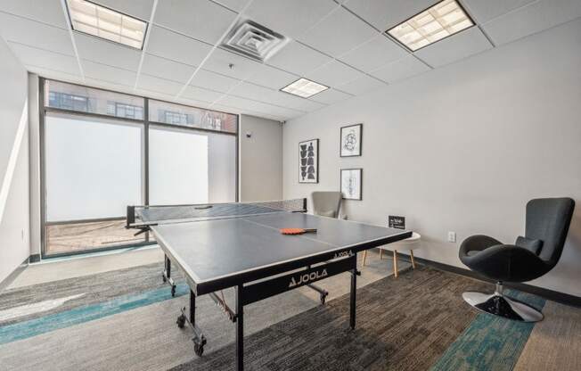 a games room with a ping pong table and chairs