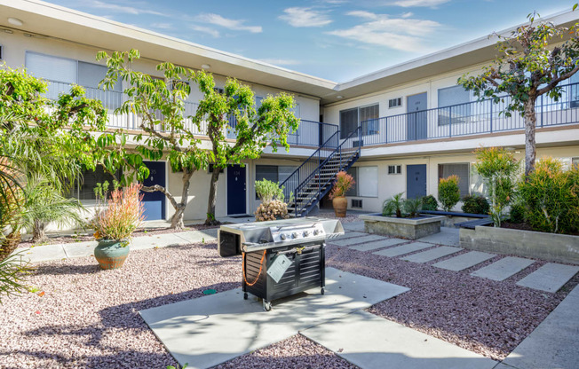 a patio with a grill and a building with a staircase