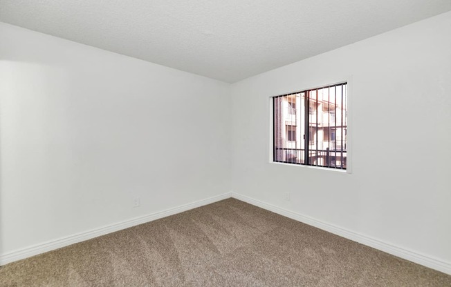 A room with a window and carpeted floor at Urban WalkApartments on 6th Avenue, Phoenix 85016