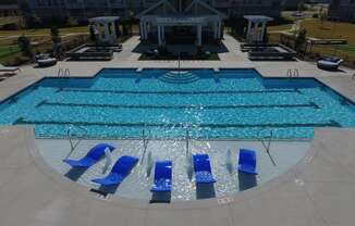 a swimming pool with blue lounge chairs in front of a hotel pool