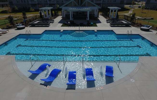 a swimming pool with blue lounge chairs in front of a hotel pool