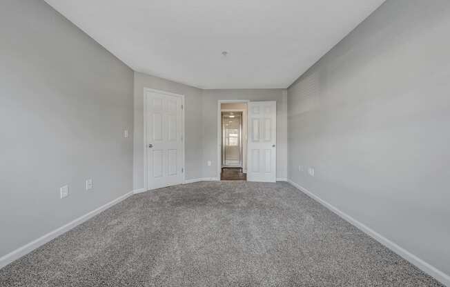 A room with a carpeted floor and two doors.