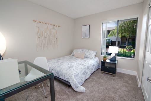 Model apartment spare bedroom with a bed and a desk and a window