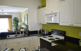 Kitchen with white cabinets, black granite countertops and an opening with a view through to the living room