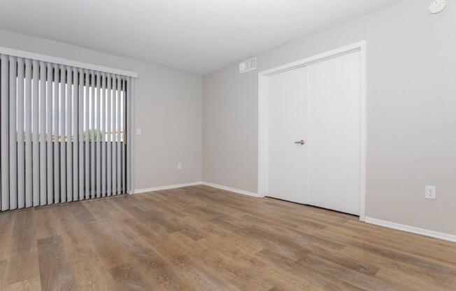 A room with a white door and a window with blinds.