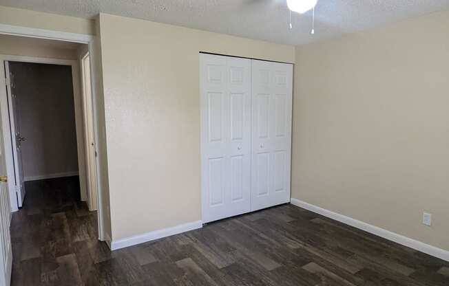 an empty living room with wood flooring and a ceiling fan