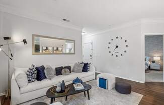 a living room with a white couch and a clock on the wall