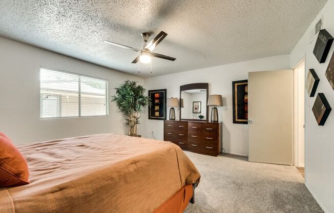 the master bedroom has a large bed and a ceiling fan