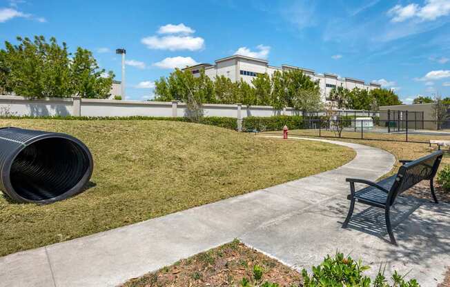 A park with a bench, a fire hydrant, and a tree.