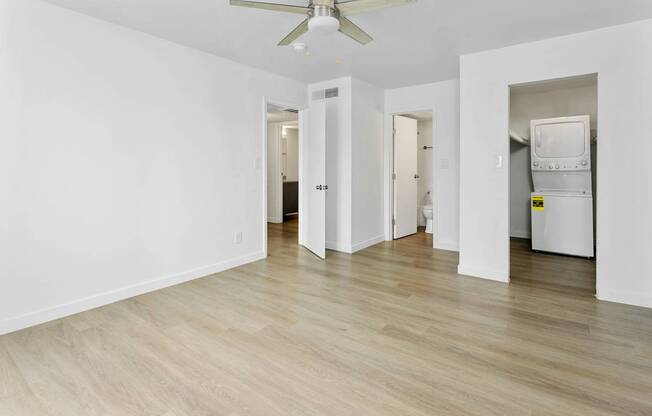 A room with a ceiling fan and light, and a white fridge in the corner.