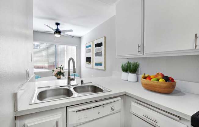 a white kitchen with a sink and a window