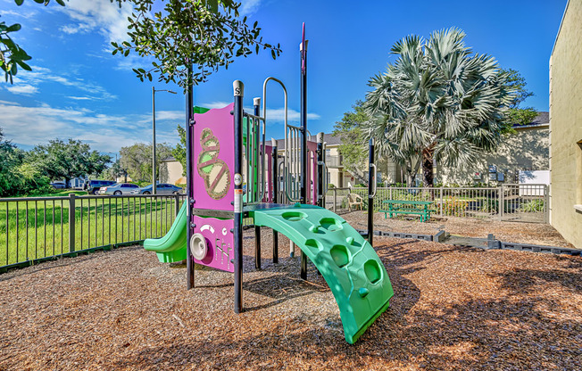 A playground with a pink and green slide.