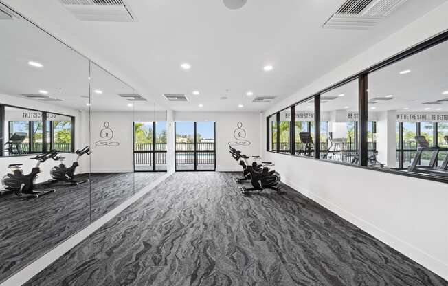 A gym with exercise machines and windows in a building
