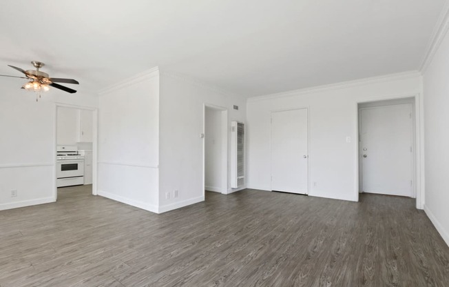 an empty living room with white walls and a ceiling fan