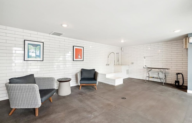 a living room with chairs and a bathroom with a tub and a sink