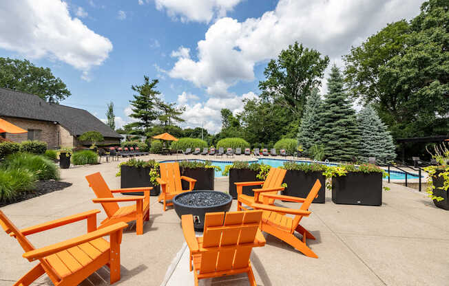 an outdoor patio with orange chairs and a fire pit and a pool