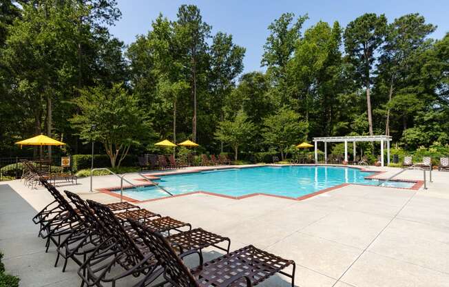 a swimming pool with chaise lounge chairs and umbrellas