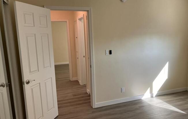 A room with a white door and wooden flooring.