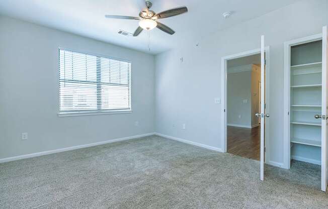 A room with a ceiling fan and a window with blinds.