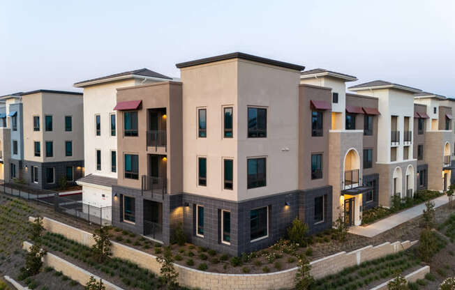 A row of modern houses with dark roofs and light walls.