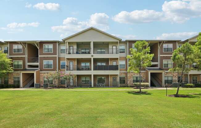 A large apartment complex with multiple balconies and a green lawn in front.