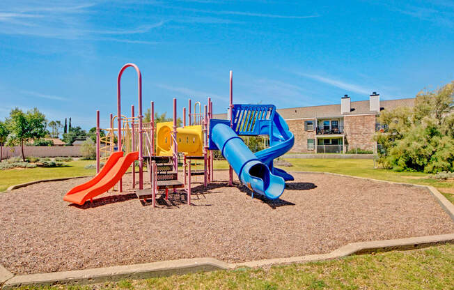 A colorful playground here at Cypress Pointe with slides, climbing structures, and open play areas designed for active outdoor fun. A spacious grassy setting with surrounding apartment homes creates a safe and welcoming environment for residents and families.