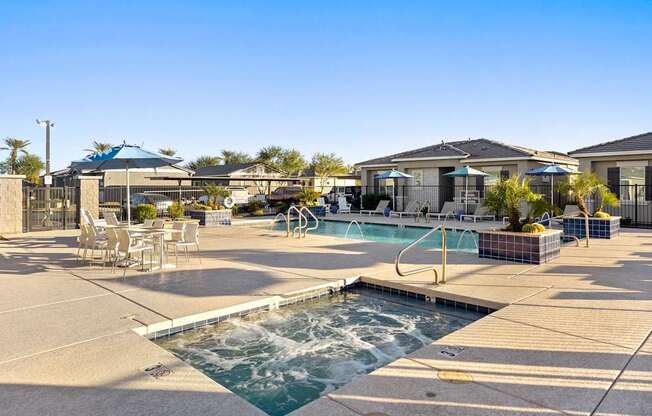 A pool area with a hot tub and lounge chairs.