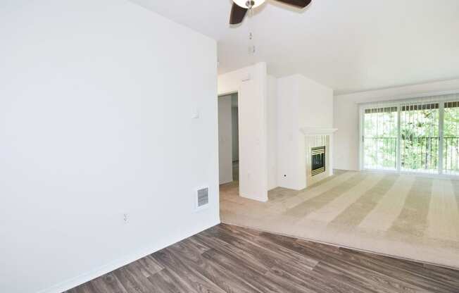 an empty living room with a fireplace and a ceiling fan