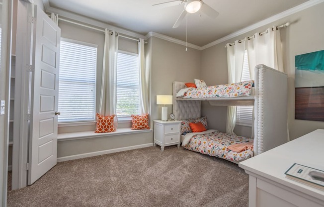staged bedroom with carpeted flooring, windows, and ceiling fan