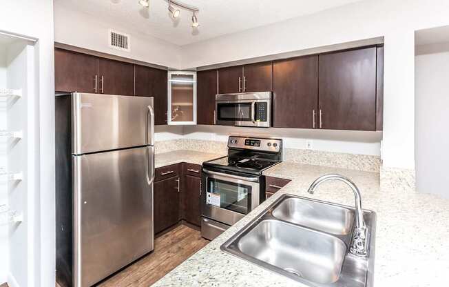 A kitchen with a stainless steel refrigerator, microwave, oven, and sink.