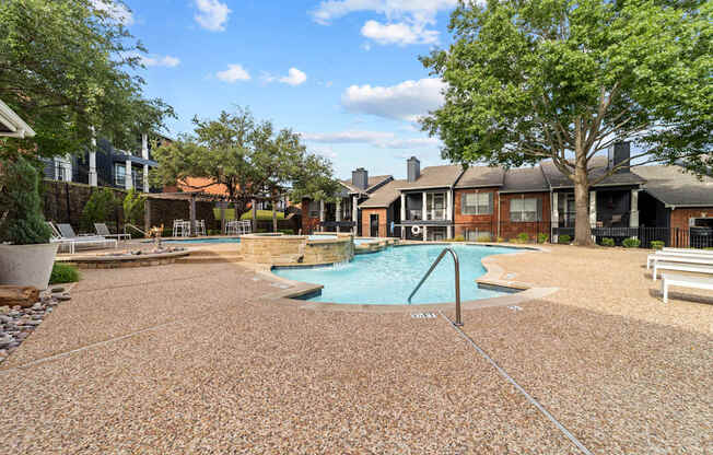 A pool surrounded by a brick patio and houses.