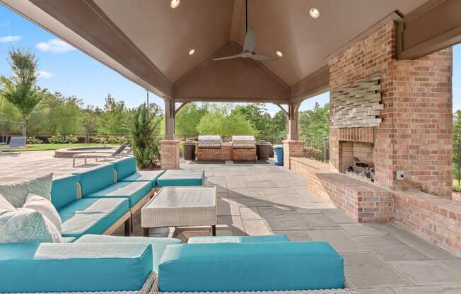 a covered patio with blue couches and a fireplace