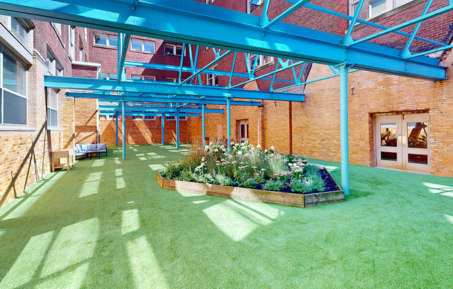 a patio with green grass and a flower bed in front of a brick building