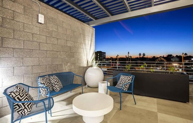 Rooftop patio with two blue chairs and a white coffee table