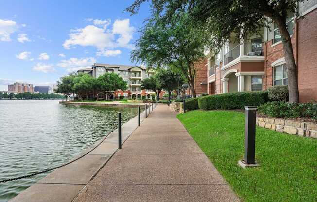 A walkway next to a body of water with a building in the background.