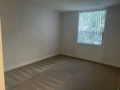 an empty room with a window and a wooden floor