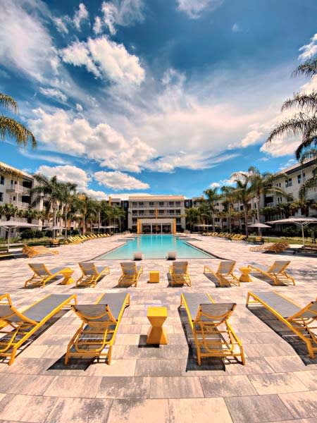 a swimming pool with yellow lounge chairs and a building in the background  at Fusion, Florida, 32256