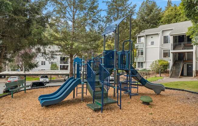 A playground with a blue slide and a green railing at Clackamas Trails Apartments, Oregon, 97222