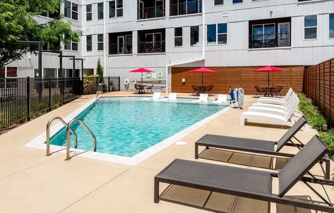 a swimming pool with lounge chairs and a building in the background at Grand Flats, St. Louis, 63104