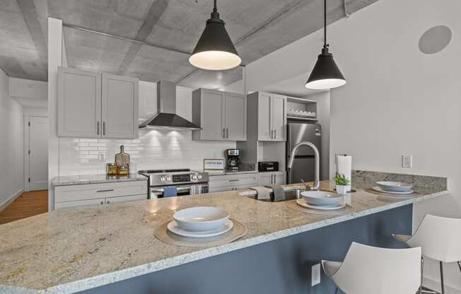 a kitchen with white cabinets and a large island with a granite countertop  at The Icon, Richmond, Virginia