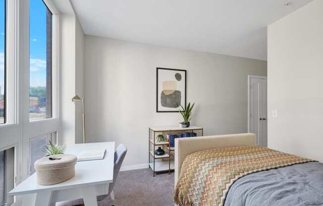 a bedroom with a large window and a desk with a chair