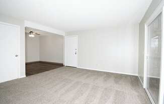 A room with a carpeted floor and a ceiling fan.